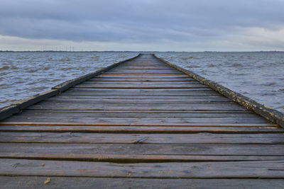 Wooden pier over sea against sky