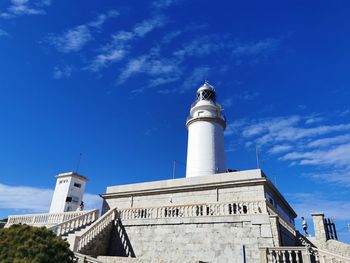 Low angle view of lighthouse by building against sky