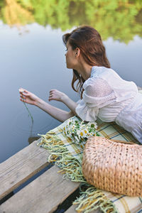 Side view of woman sitting on chair at beach