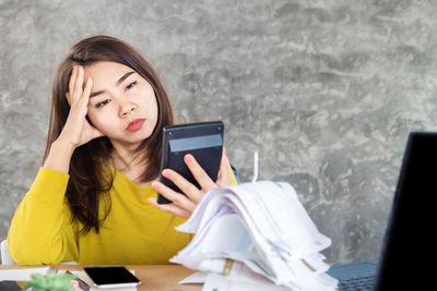 Young woman using mobile phone while sitting on table