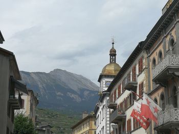 Low angle view of buildings and mountains against sky