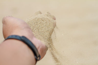 Close-up of woman hand on sand