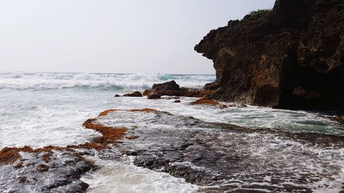 Rock formation on beach against sky