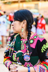 Young woman looking away while standing outdoors