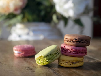 Close-up of macrons on wooden with flowers in white vase background table