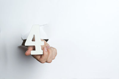 Close-up of hand holding paper over white background