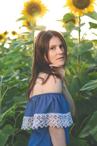 Portrait of young woman standing against plants