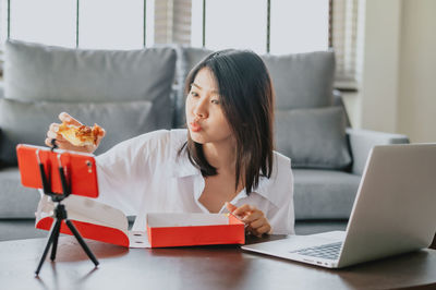 Woman using phone while sitting on table