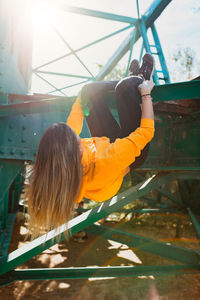 Rear view of woman hanging on railway bridge