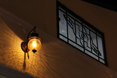 Low angle view of illuminated lamp hanging on window