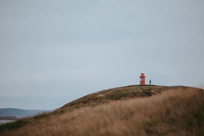 Low angle view of lighthouse on hill against sky