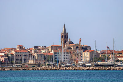 Buildings by sea against clear sky