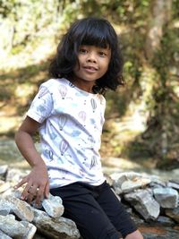 Portrait of cute girl siting on stones by stream