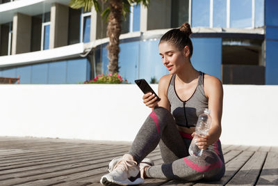 Young woman using mobile phone while sitting outdoors