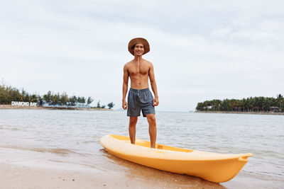 Rear view of shirtless man standing in boat