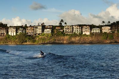 High angle view of man longboarding on sea against cityscape