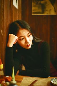 Portrait of young woman sitting on table at restaurant