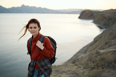 Portrait of young woman standing at sea shore