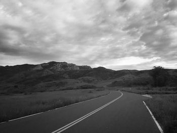 Country road against cloudy sky