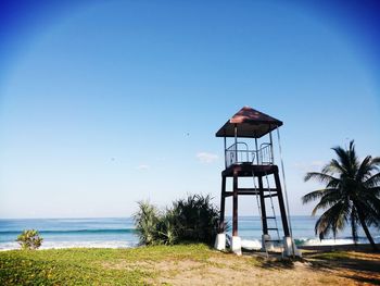 Lifeguard hut on beach against clear blue sky
