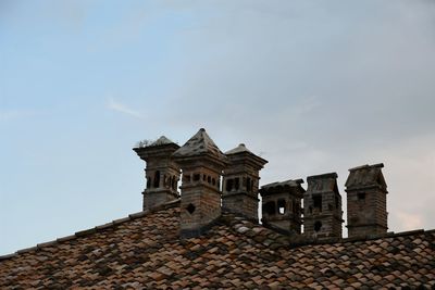 Old, brick chimneys on a roof against cloudy sky, italyi