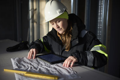 Female engineer checking plans on digital tablet