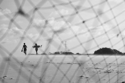 People playing on fence against sky