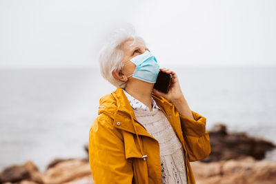 Side view of woman drinking water while standing at beach