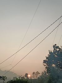Low angle view of power cables against sky at dusk