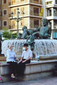 Statue of man sitting by fountain