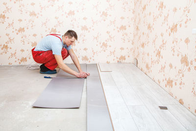 Man putting hardwood floor panels in home