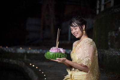 Portrait of young woman holding sparkler at night