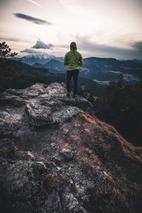 Rear view of man standing on rock against sky