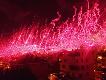 Firework display in city against sky at night