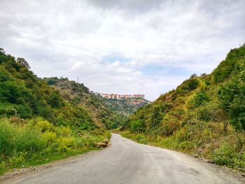 Road amidst trees against sky