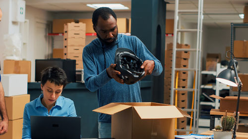 Side view of man using laptop while standing in gym