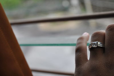 Cropped hand of woman touching window