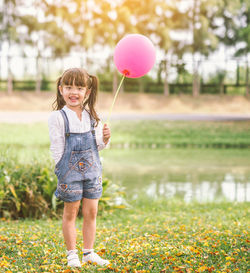 Full length portrait of smiling girl standing at park