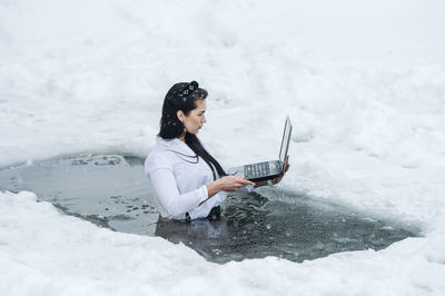 Side view of young woman skiing on snow covered field