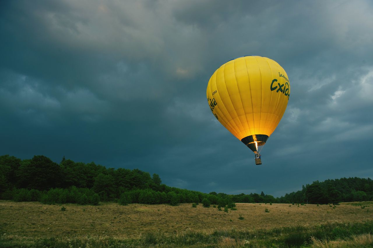 sky, cloud - sky, tranquility, scenics, tranquil scene, mid-air, hot air balloon, landscape, cloud, flying, nature, adventure, tree, parachute, cloudy, yellow, beauty in nature, low angle view, green color, sport