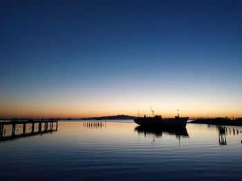 Silhouette boats in lake against clear sky during sunset