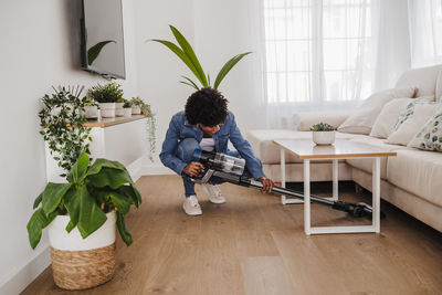 Young woman cleaning under coffee table in living room at home