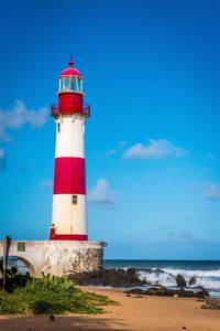Lighthouse on beach against blue sky