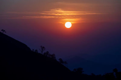 Scenic view of silhouette mountains against orange sky