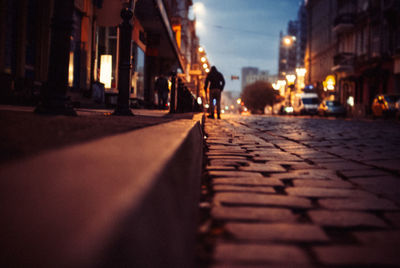 Surface level view of cobbled street amidst buildings at night