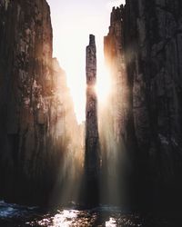 Sunlight streaming through by cliff in sea