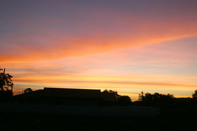 Silhouette trees and buildings against sky during sunset