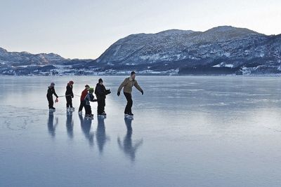 People on beach against sky during winter