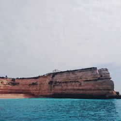 Rock formations by sea against sky