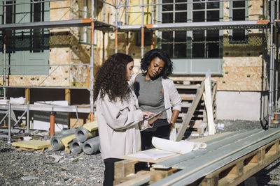 Portrait of young woman standing against building